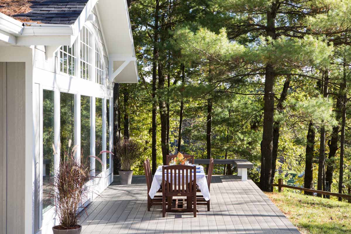 Dining table with flowy white table cloth on the deck of a home in the forest