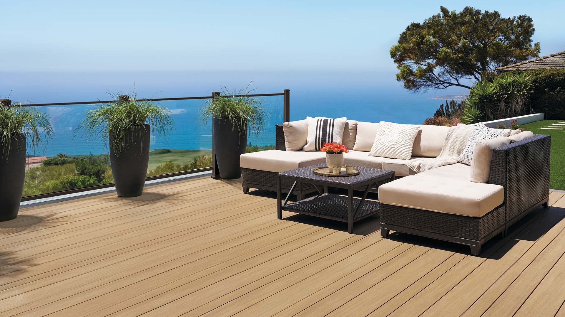 Couch on light brown deck that looks out on the water from a hill